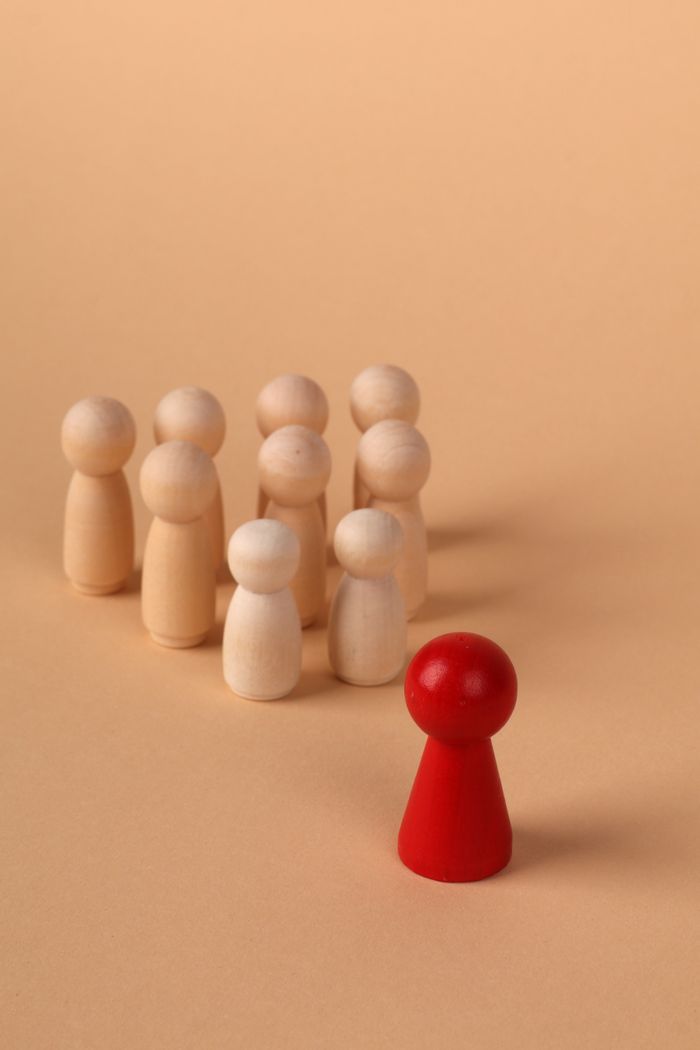 Service Wooden figures representing leadership and individuality on a neutral background.