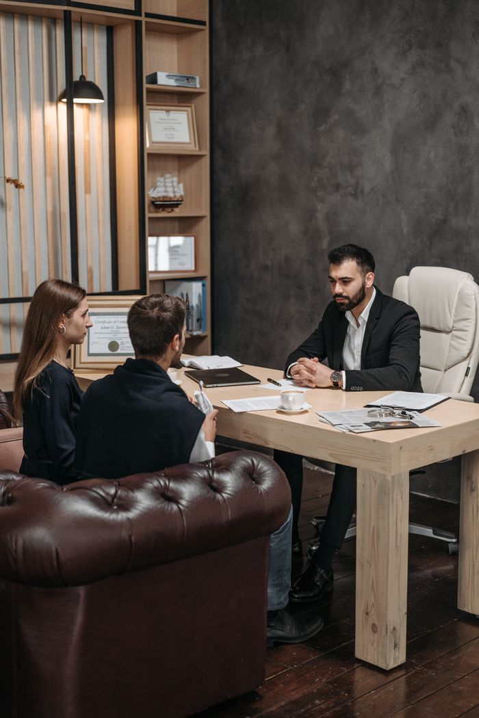 Service A professional business meeting with three people discussing documents in an office setting.